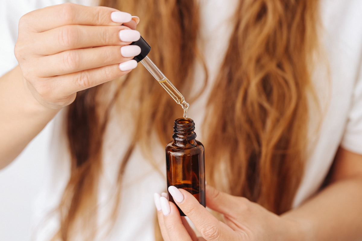 Hands holding a dropper bottle of oil over an open palm