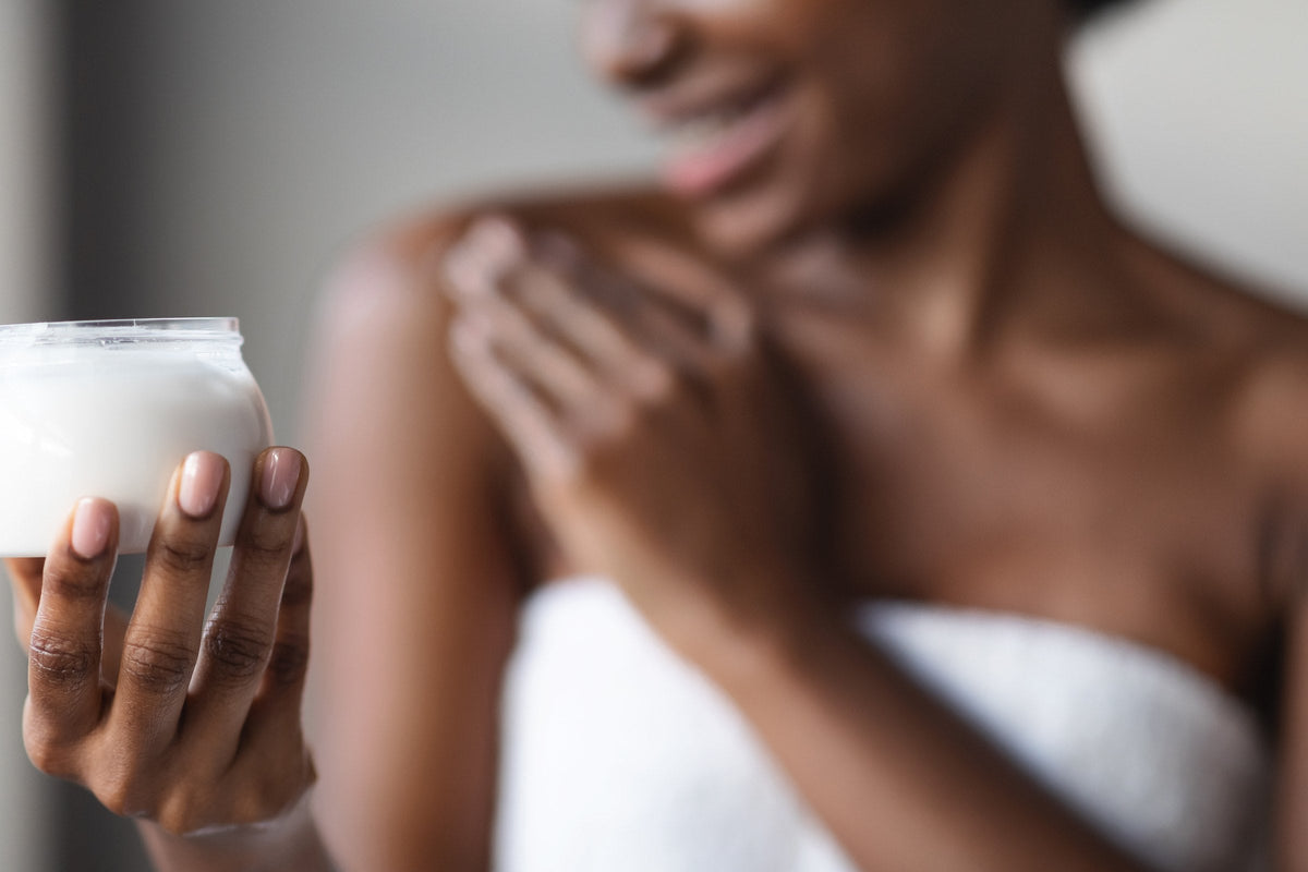 A woman holding a jar of body lotion