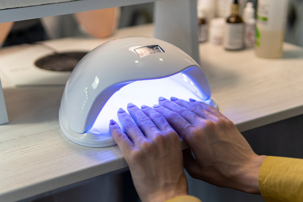 A woman drying gel polish under a UV nail lamp at home