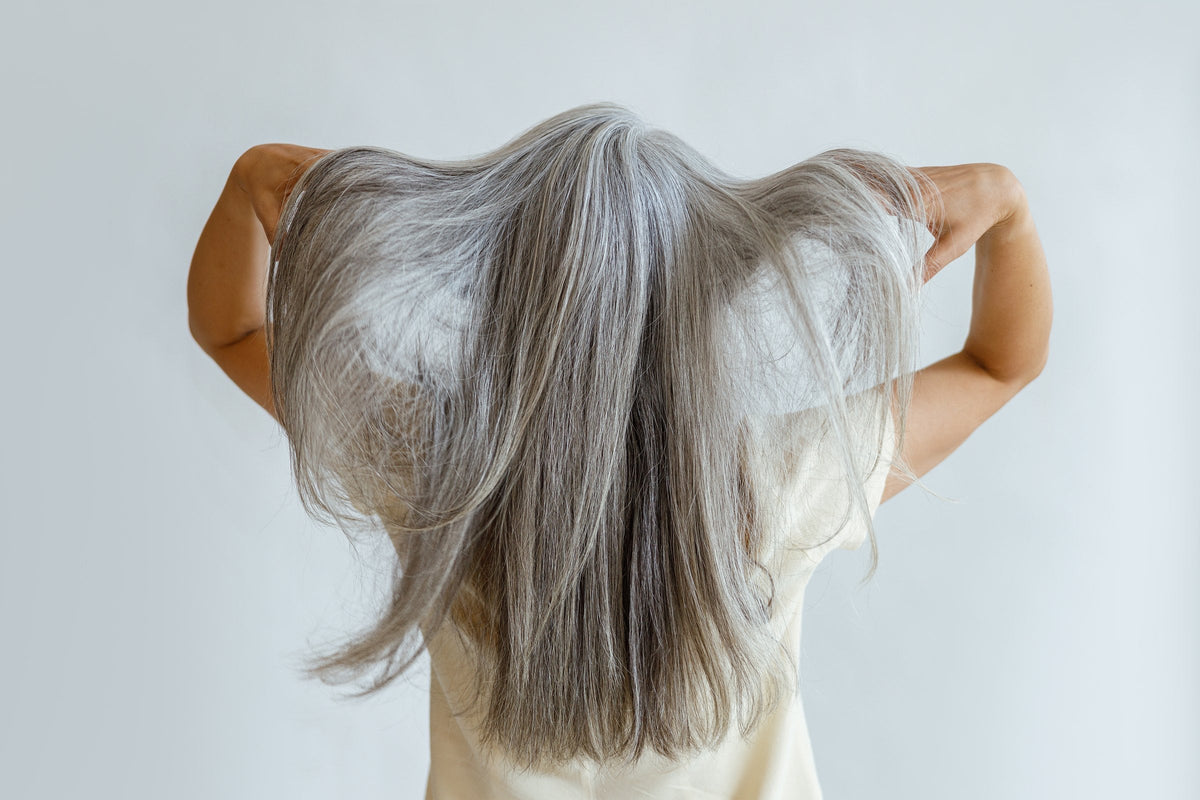A woman with long loose grey hair in a yellow blouse