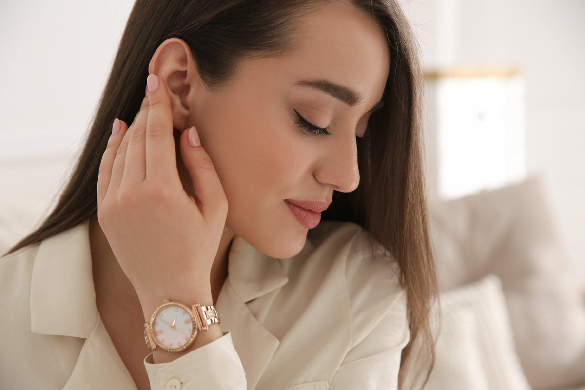 A woman wearing a rose gold-tone wristwatch