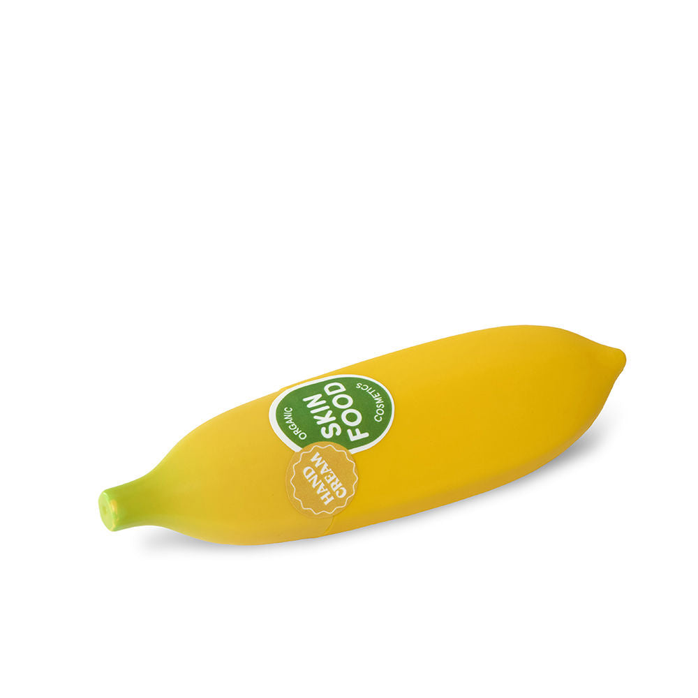 Yellow banana-shaped hand cream with green stem and two stickers on smooth surface, IDC Institute