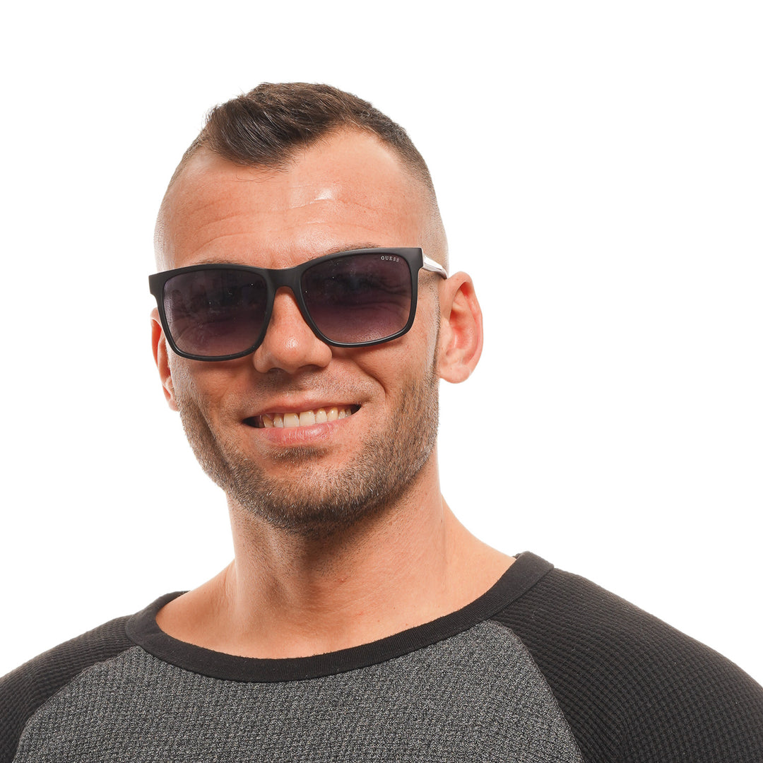 Black rectangular sunglasses on neutral background with gradient lenses and visible logo on temple