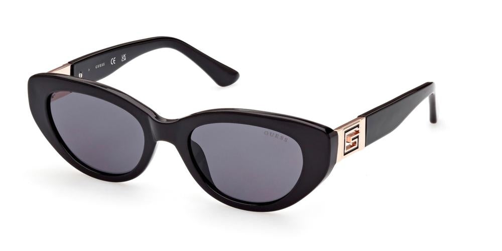 Black cat-eye sunglasses with gold logo accents on temples and dark tinted lenses on white background
