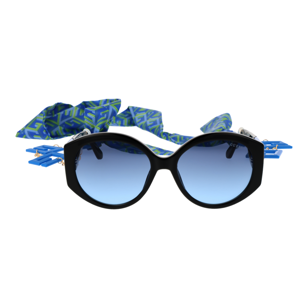 Black cat-eye sunglasses with gradient blue lenses, blue-green patterned scarf and gold chain charms