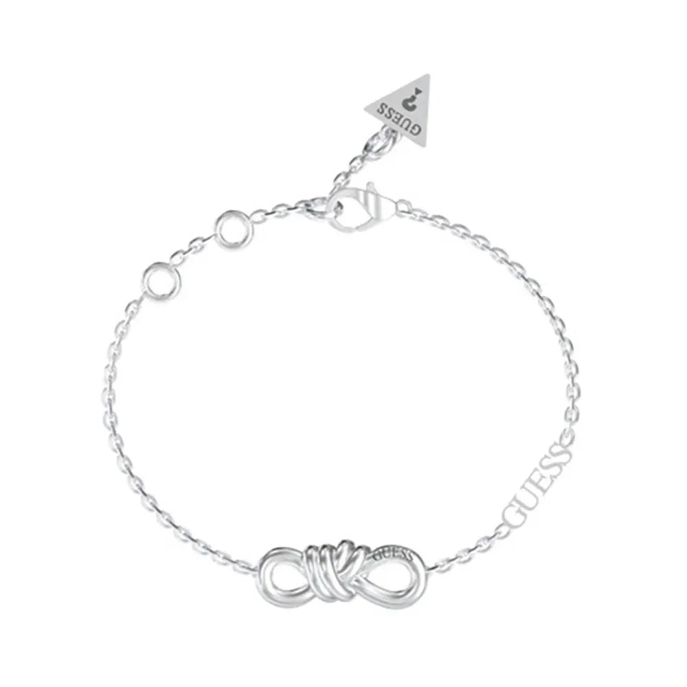 Silver chain bracelet featuring an infinity knot charm and small triangular tag on a reflective surface