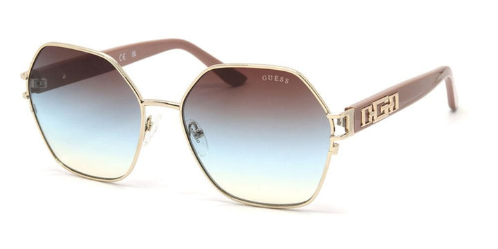 Gold geometric sunglasses with blue-to-brown gradient lenses and decorative gold temple accents on a neutral background